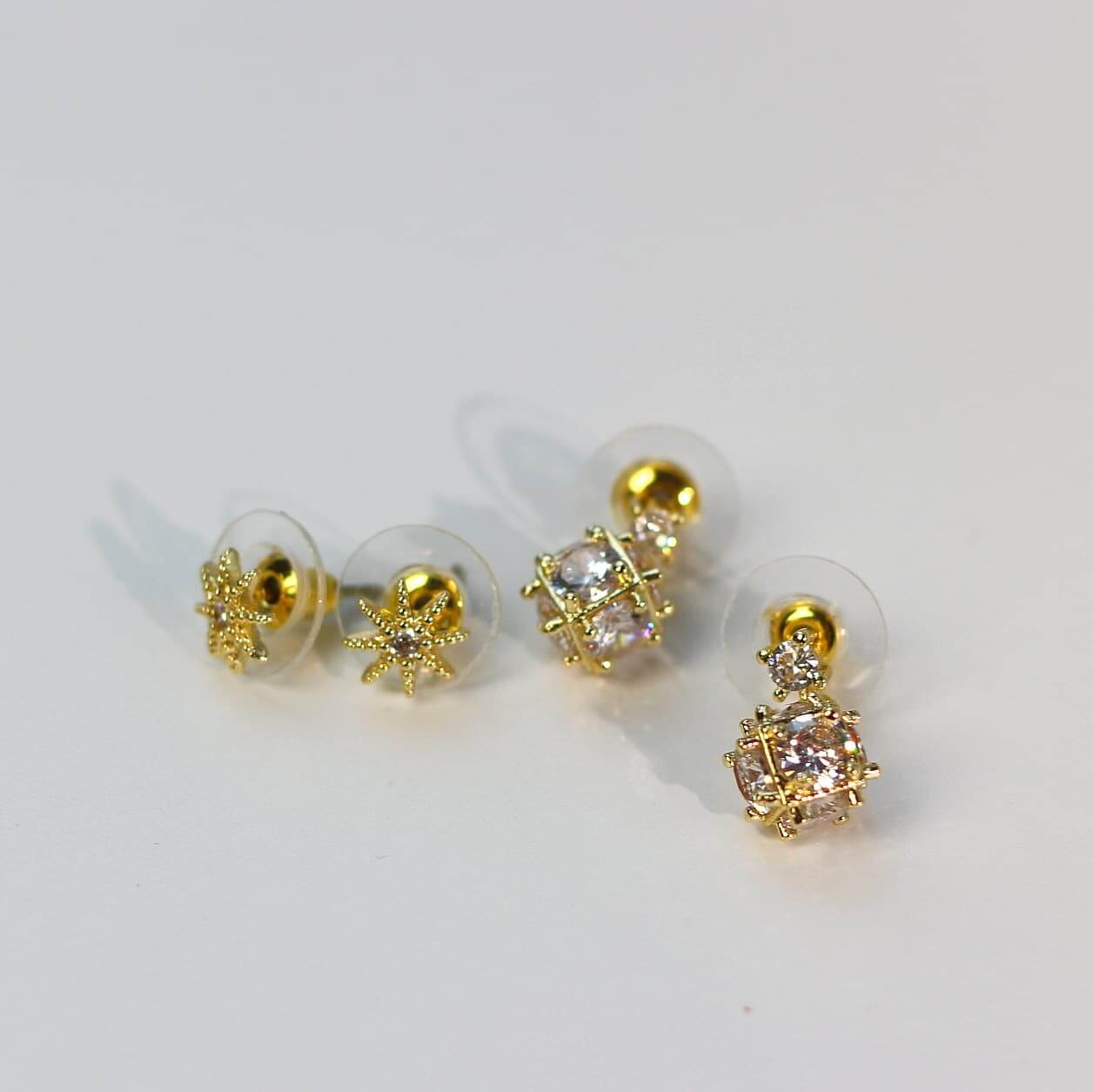 Flat lay photo of Starlume Earring Set, highlighting faceted crystals and star motifs in gold tone.