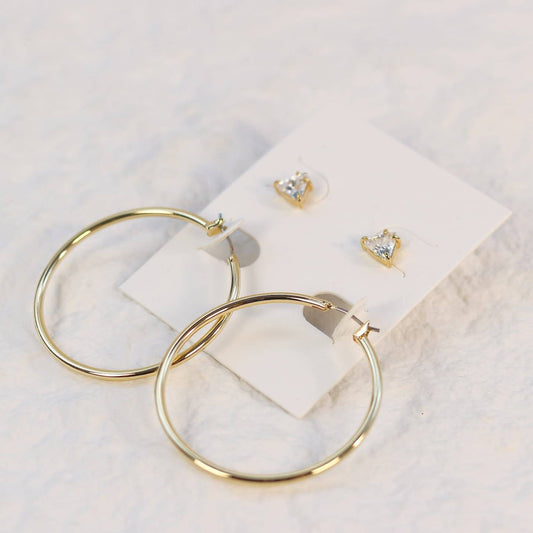 Triad Glow Earring Set with triangular 6mm CZ studs and large 42mm gold hoops with post-back closures, displayed on a cream card with soft front lighting.