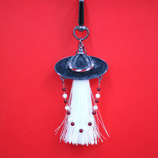 Close up of White Spirit Hunter Key Ring featuring a white tassel and Korean traditional hat shape with gentle glowing detail.