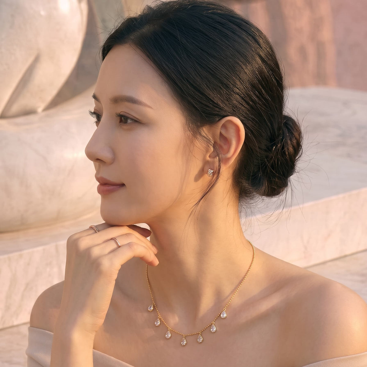 Side profile of a woman wearing the GinakimKR Aria Teardrop Station Necklace in gold, showcasing the elegant drop design and ball chain on an off-the-shoulder outfit.