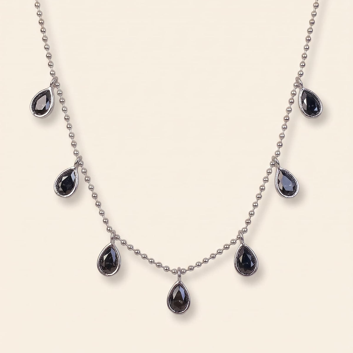 The Aria Teardrop Station Necklace by GinakimKR in silver with black diamond Czech glass stones. Minimalist silver beaded chain necklace with dark teardrop charms.