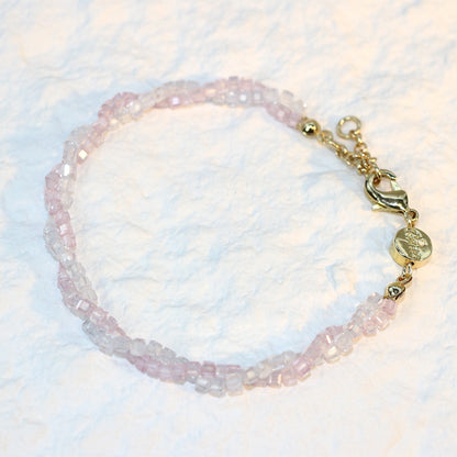 A close-up of the Blush Prism Bracelet, showcasing warm champagne-pink crystal beads with a luminous finish. The stretch bracelet features a sparkling CZ accent bead, styled on a woman’s wrist with soft natural lighting for an elegant, feminine look.