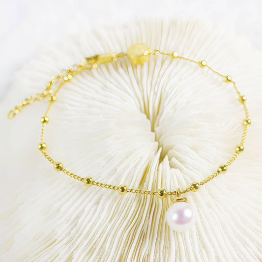 Elegant gold bracelet with delicate chain, small gold beads, and a single pearl charm