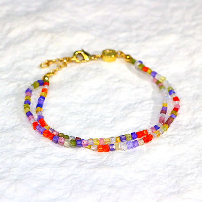 A close-up of the Joy Prism Bracelet featuring soft blush-toned crystal beads with a subtle iridescent sheen. The bracelet is stretch-fit and accented with a delicate CZ bead, styled elegantly on a woman's wrist in natural sunlight.