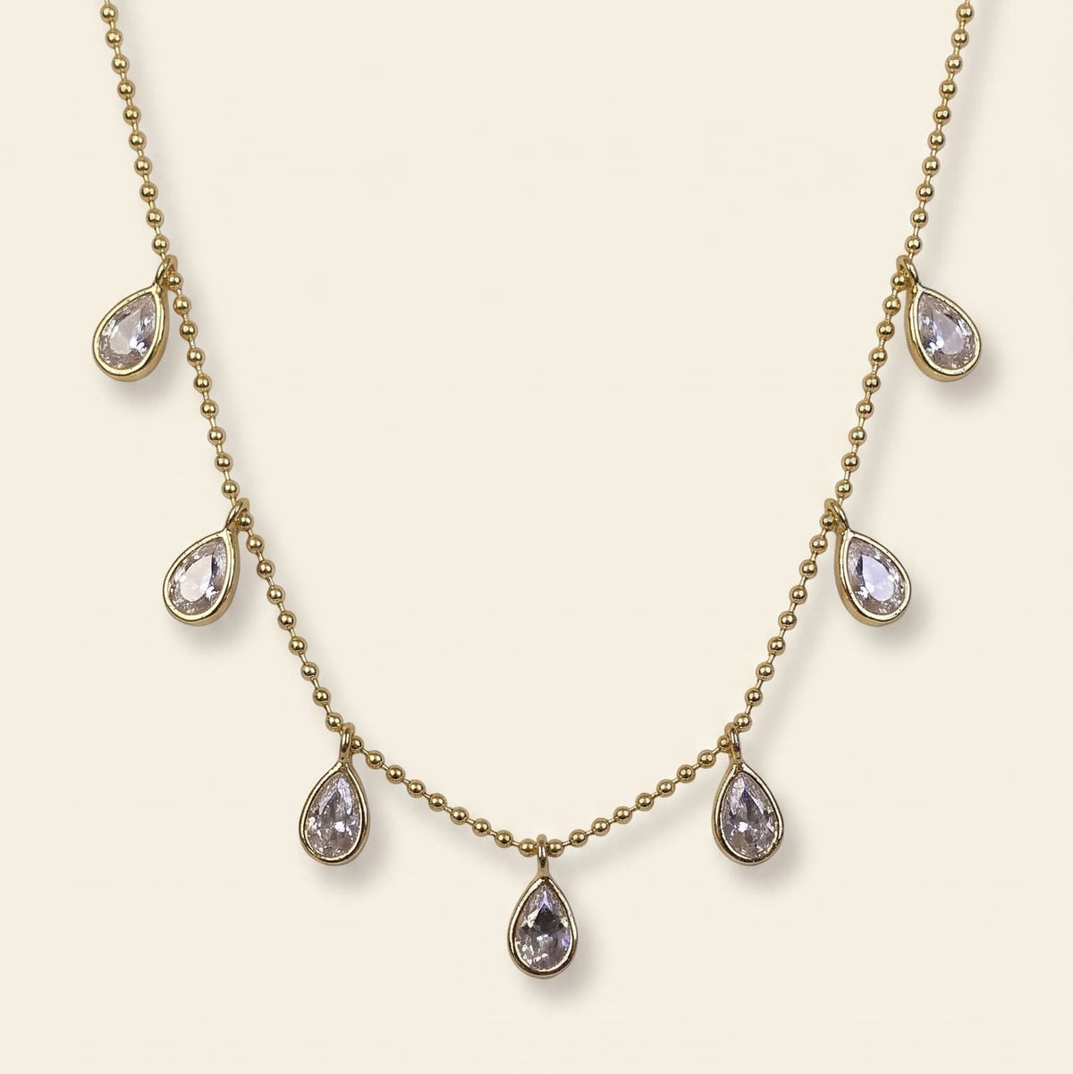 The Aria Teardrop Station Necklace by GinakimKR in gold, featuring 7.5mm x 5.5mm clear Czech glass stones dangling on a delicate gold beaded chain. Minimalist daily jewelry, gold/cry colorway.