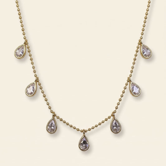 The Aria Teardrop Station Necklace by GinakimKR in gold, featuring 7.5mm x 5.5mm clear Czech glass stones dangling on a delicate gold beaded chain. Minimalist daily jewelry, gold/cry colorway.