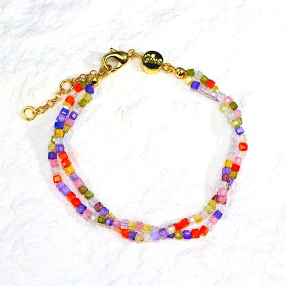 A close-up of the Joy Prism Bracelet featuring soft blush-toned crystal beads with a subtle iridescent sheen. The bracelet is stretch-fit and accented with a delicate CZ bead, styled elegantly on a woman's wrist in natural sunlight.