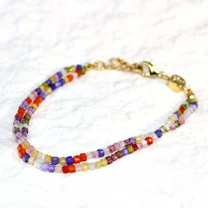 A close-up of the Joy Prism Bracelet featuring soft blush-toned crystal beads with a subtle iridescent sheen. The bracelet is stretch-fit and accented with a delicate CZ bead, styled elegantly on a woman's wrist in natural sunlight.
