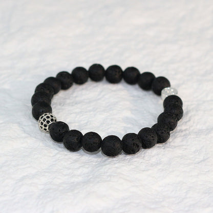Top-down image of the Lava Strength Bracelet featuring 8mm matte black lava beads, arranged in a circular shape on a white textured surface.