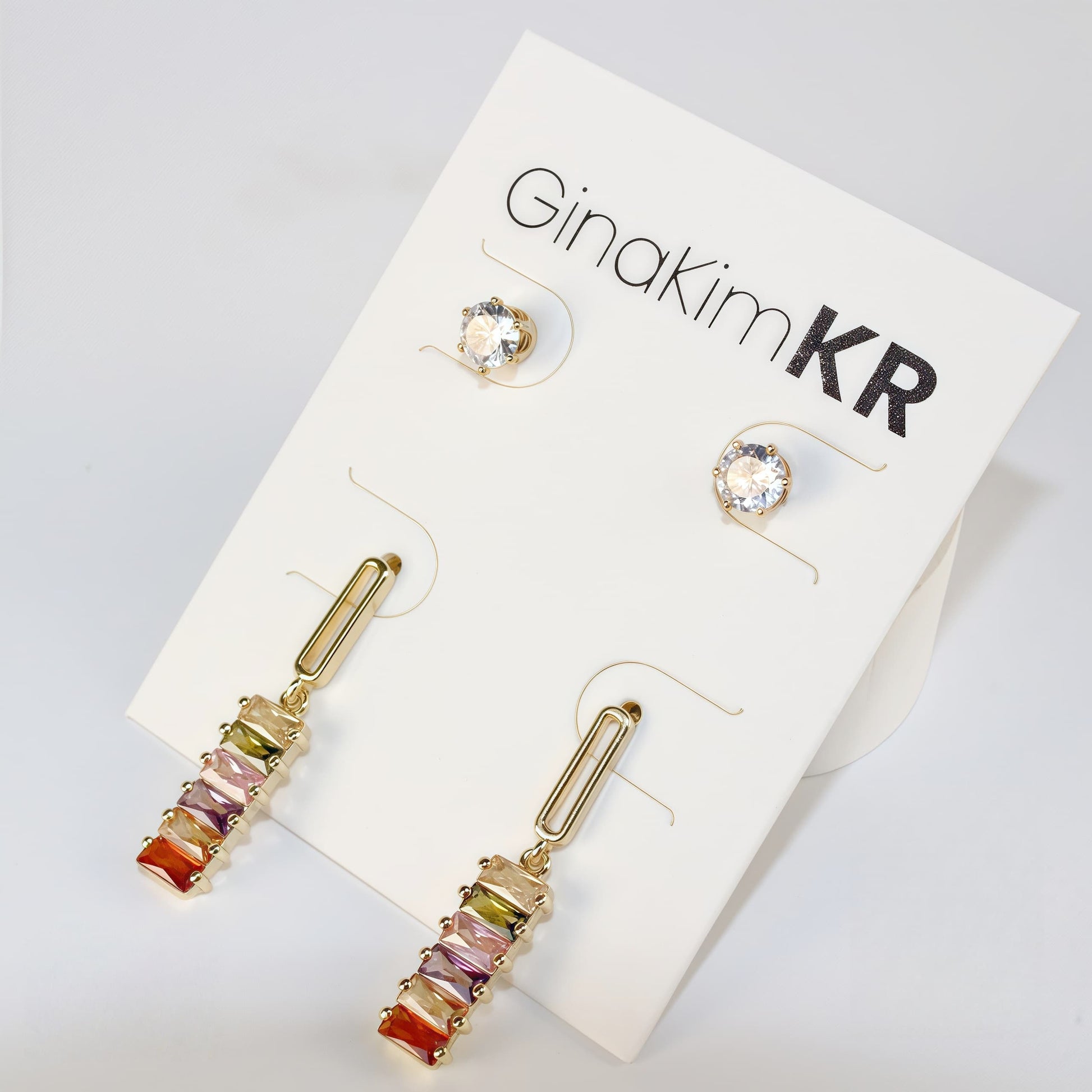Angled shot of multicolor Lightfall Duo earrings with cylindrical beads and gold settings, shown in soft daylight.