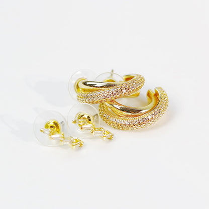 Scattered display of GinaKimKR Luna Curve gold earrings set on light surface, capturing elegant curved silhouettes.