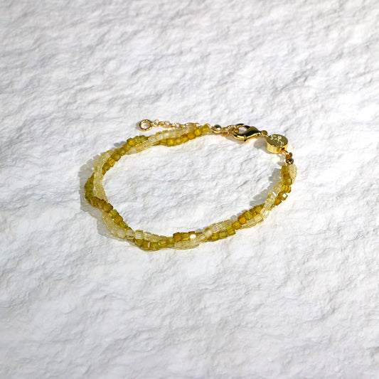 A close-up of the Olive Prism Bracelet featuring soft olive green crystal beads with a subtle shimmer. The bracelet is stretch-fit and accented with a sparkling CZ bead, worn on a woman's wrist in warm natural sunlight for a calm and elegant look.