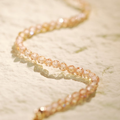 Close-up of the Champagne Light Necklace arranged in a spiral, highlighting the shimmer of CZ beads and gold accents in a clean, modern design.