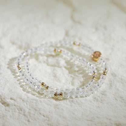 A double-row crystal quartz stretch bracelet with gold-toned accents and a Gina Kim logo tag. Clean, elegant, and handmade.