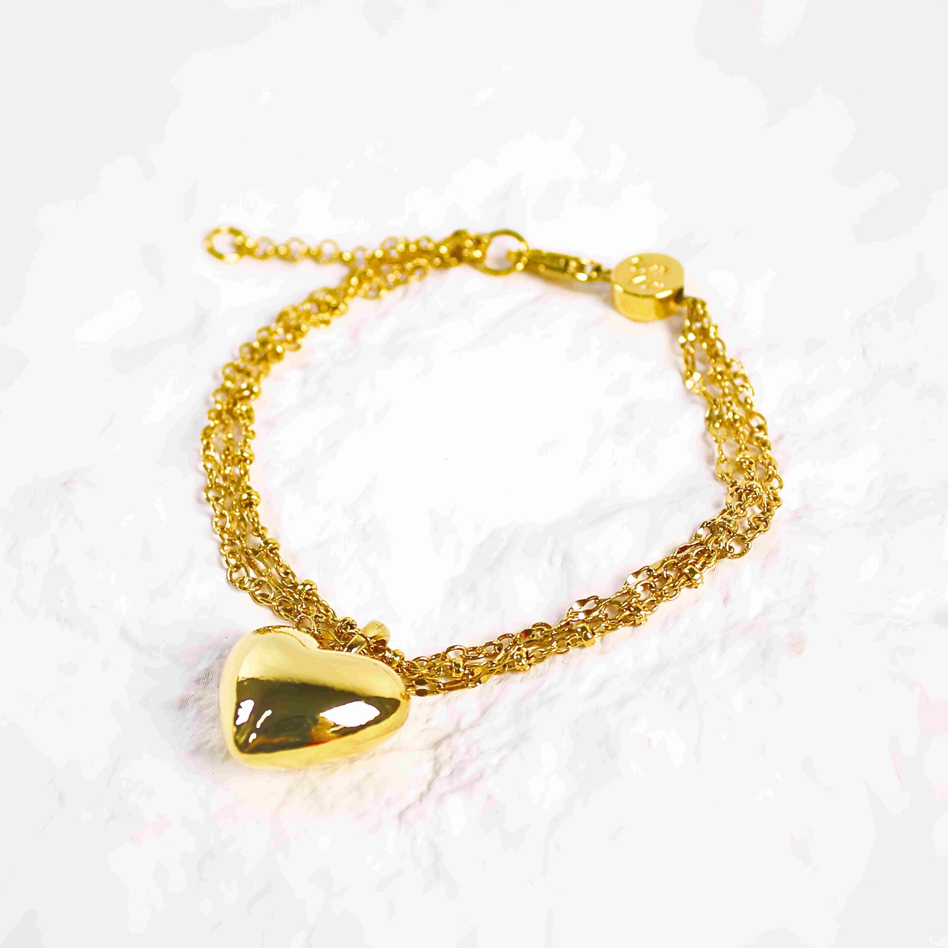 Close-up of Evergold Triple Chain Heart Bracelet with shiny gold heart pendant