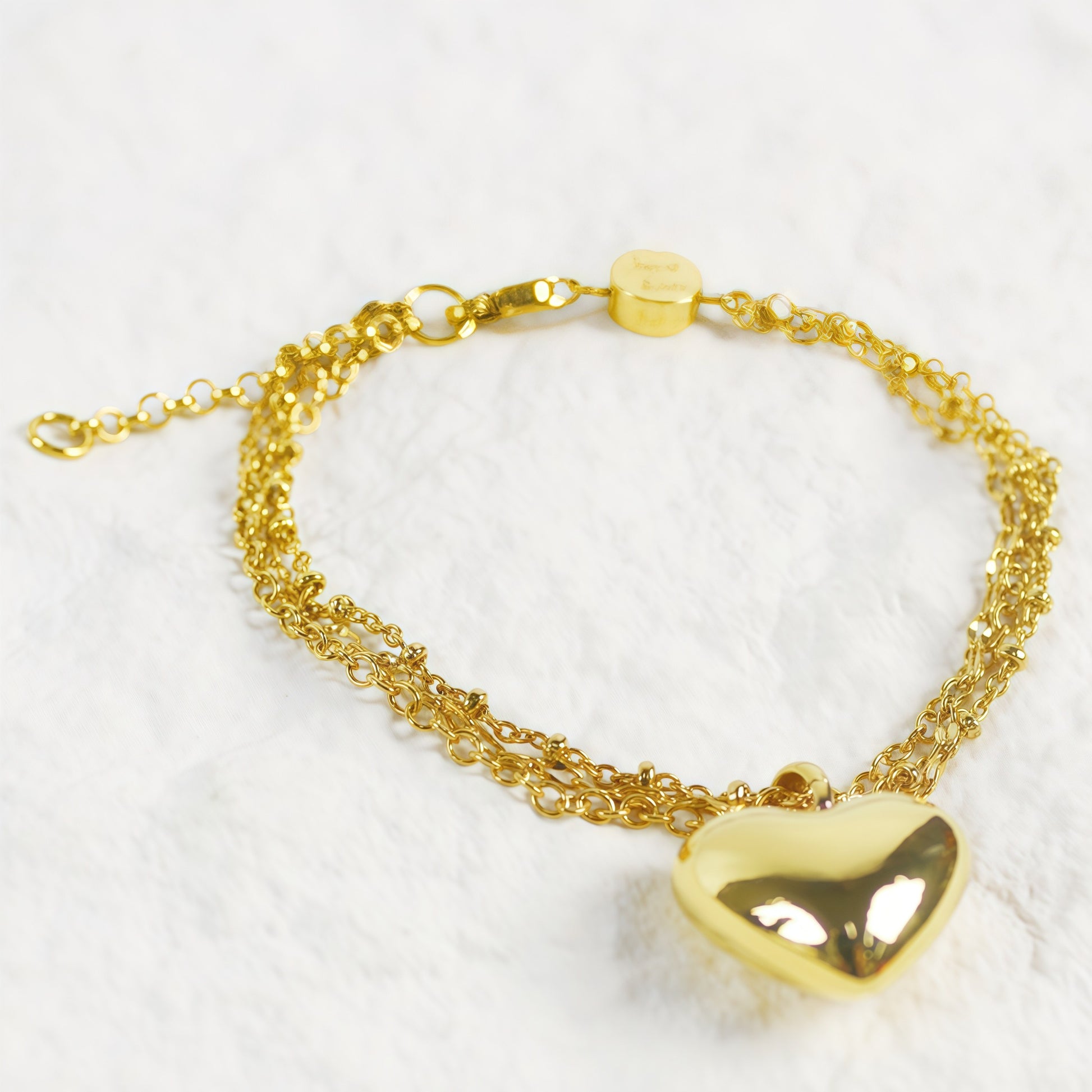 Close-up of Evergold Triple Chain Heart Bracelet with shiny gold heart pendant