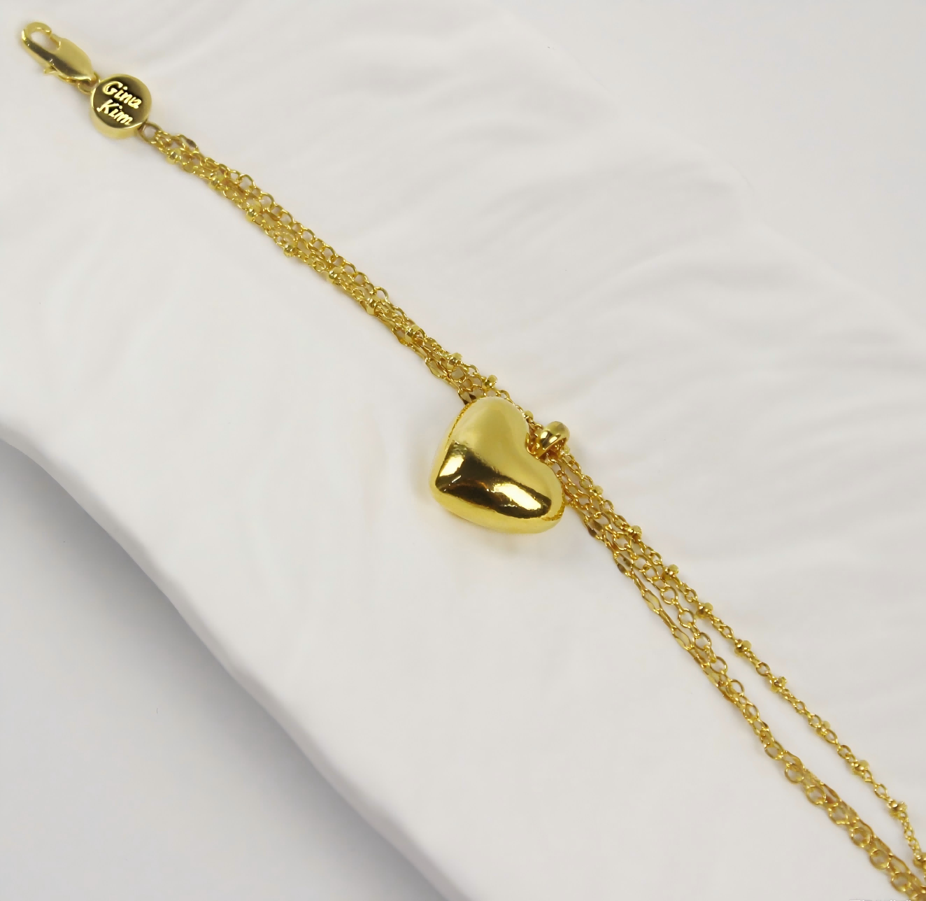 Side angle of Evergold Triple Chain Heart Bracelet showing layered gold chains