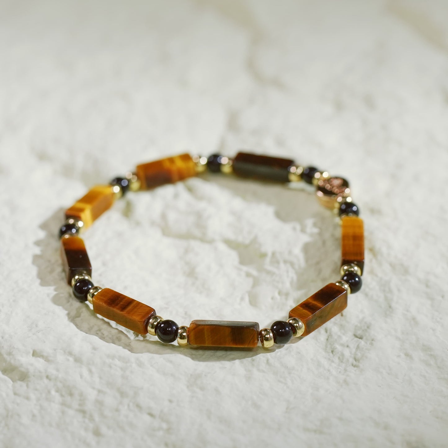 A handcrafted stretch bracelet featuring Tiger’s Eye and Onyx beads with a gold CZ accent and Gina Kim charm. Bold and grounding.