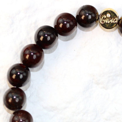 Close-up side shot of the Garnet Strength Bracelet highlighting glossy 8mm beads and the signature Gina gold tag for a refined look.