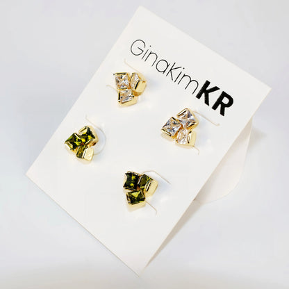 Flat lay image of Geo Trio Earring Set with three pairs of studs in clear and olive green, arranged in rows.