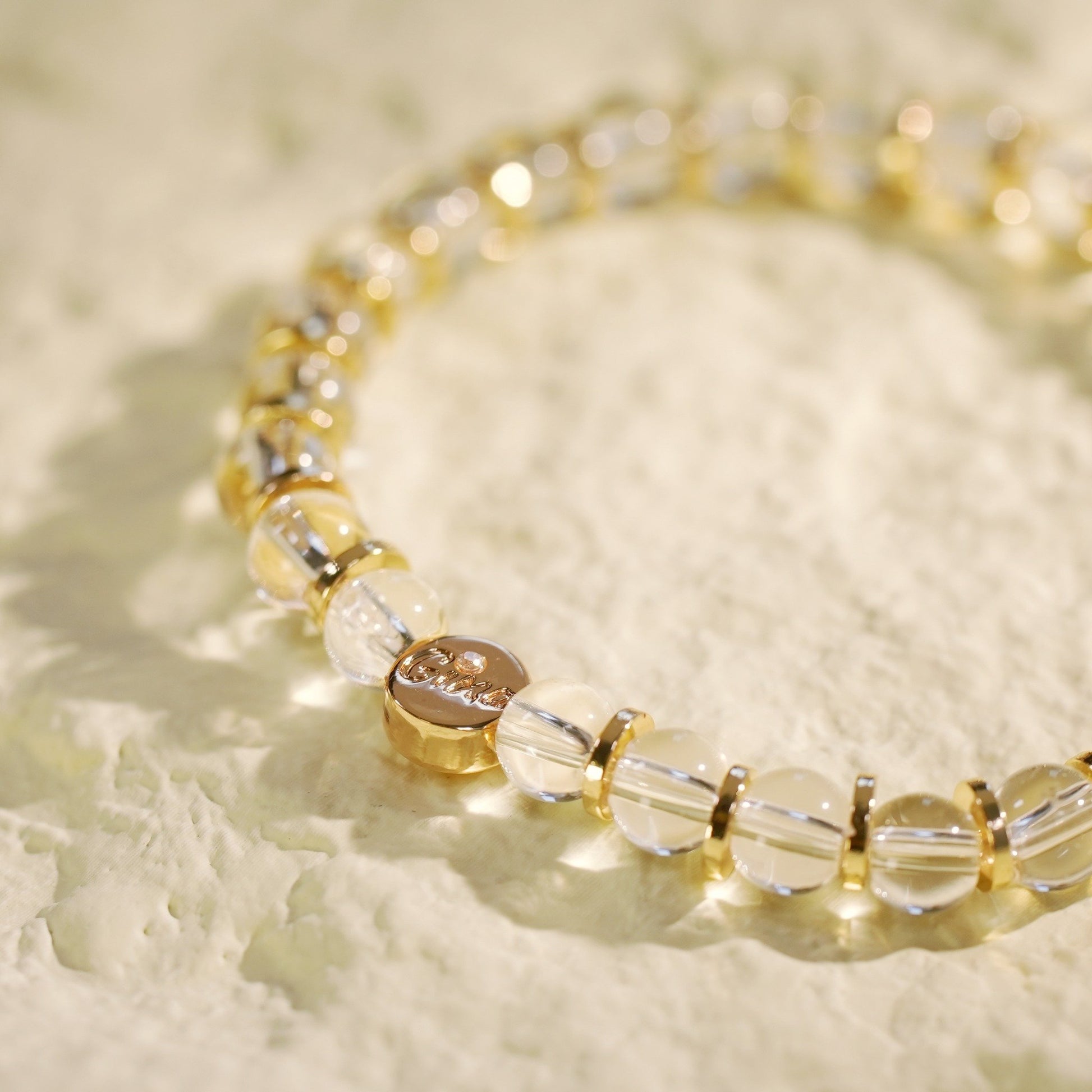 A crystal quartz stretch bracelet with gold-toned spacers, designed for clarity and elegance. Handmade by Gina Kim Jewelry.