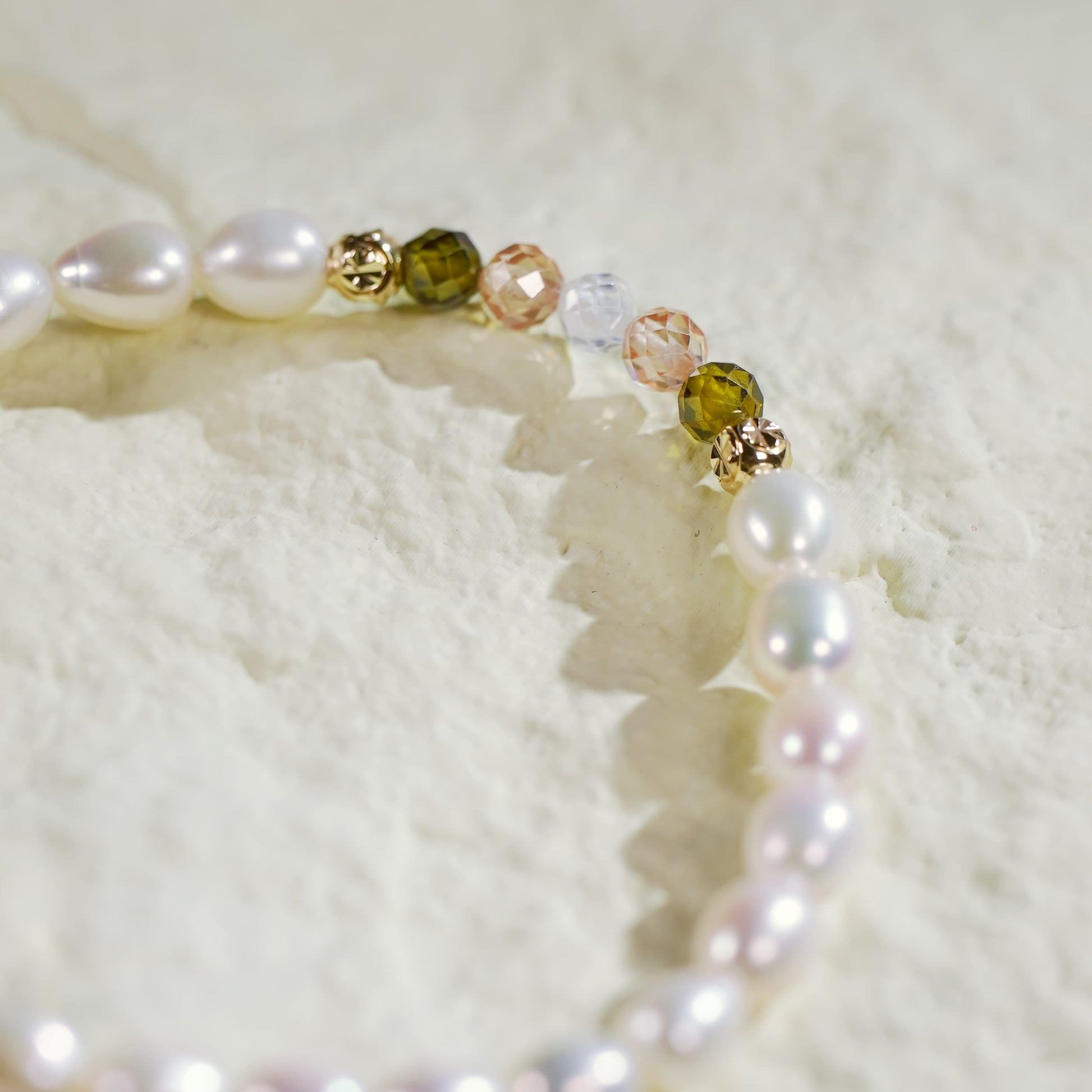 Close-up of the Harmony Light Bracelet showing alternating crystal CZ beads and pearls, finished with gold-plated accents on a softly lit fabric background.