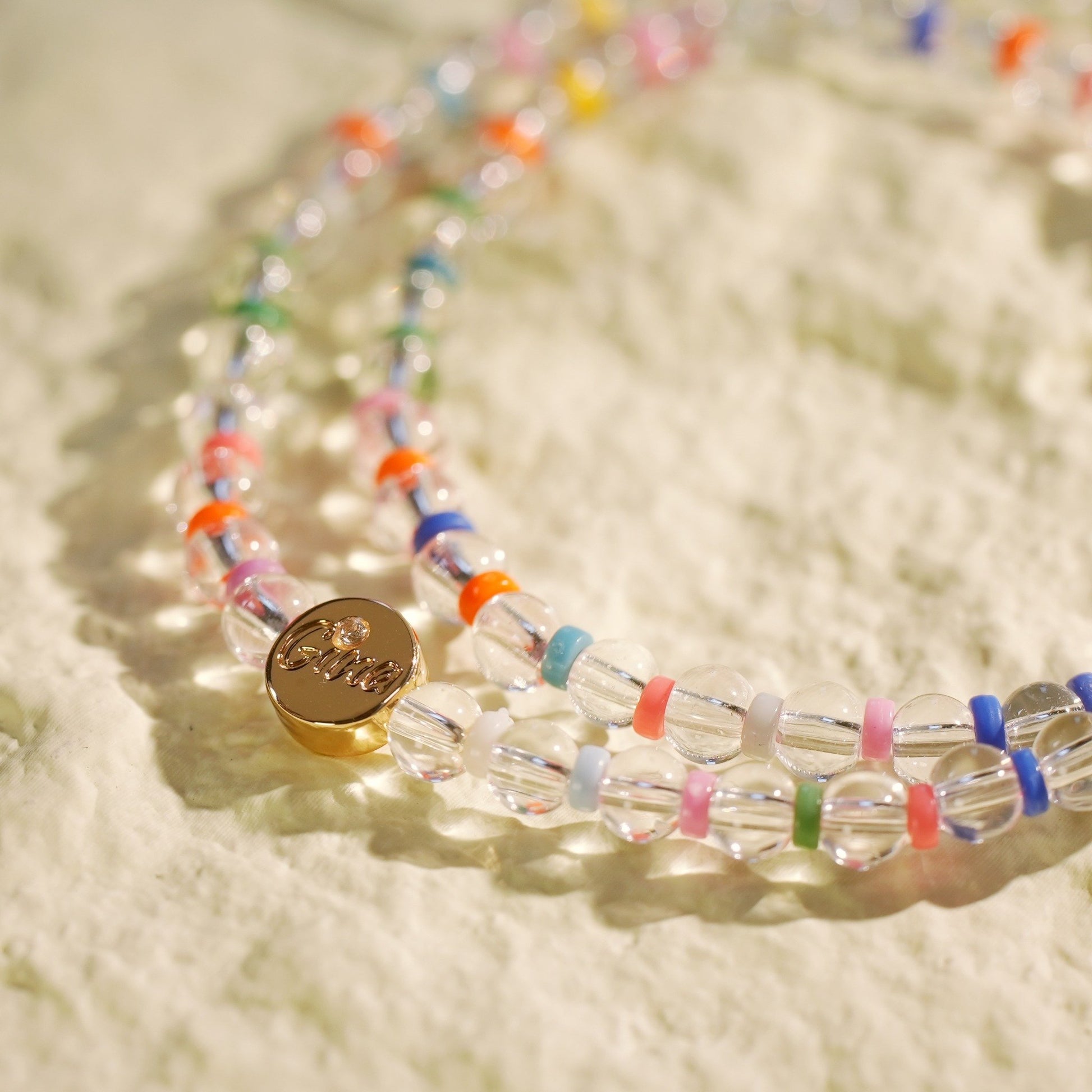 A double-row stretch bracelet made with clear crystal quartz and rainbow color beads. Light, joyful, and handmade by Gina Kim Jewelry.