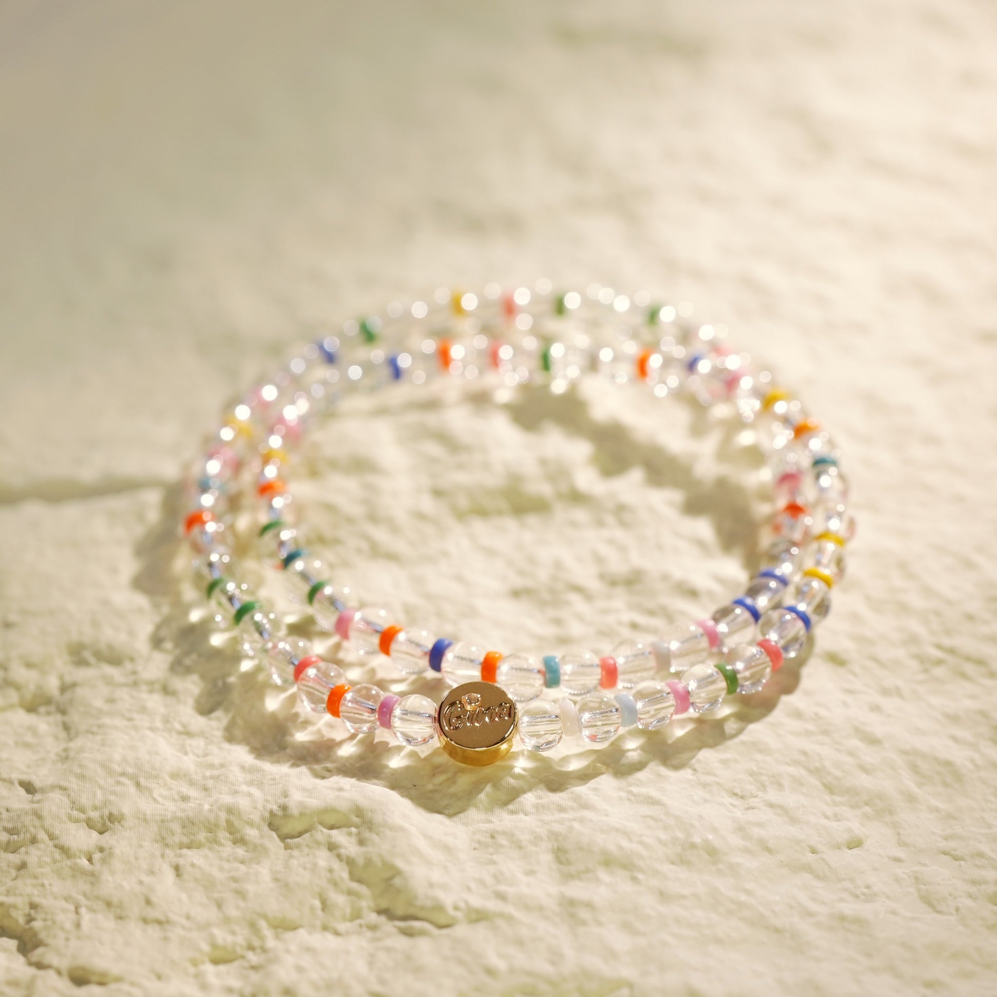 A double-row stretch bracelet made with clear crystal quartz and rainbow color beads. Light, joyful, and handmade by Gina Kim Jewelry