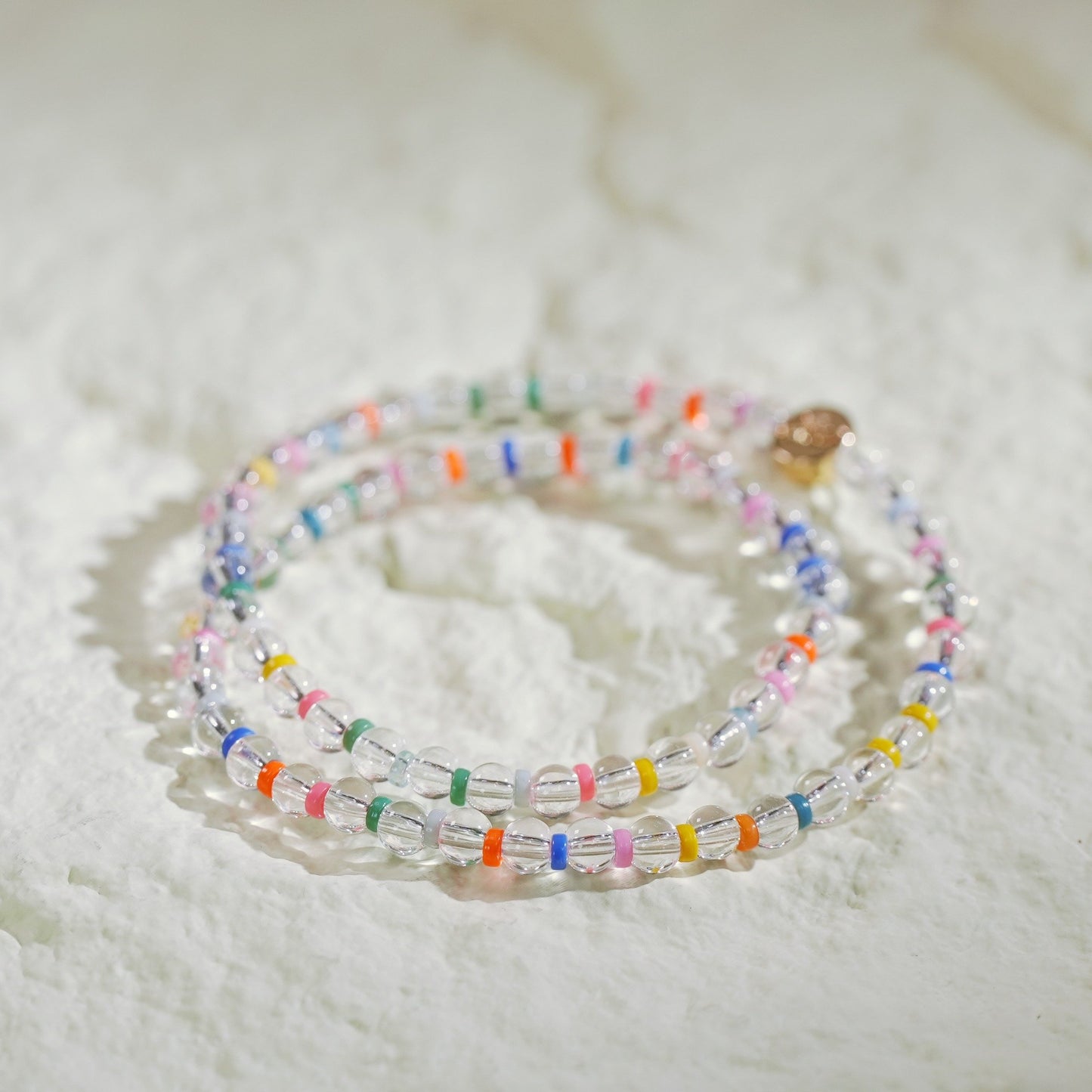 A double-row stretch bracelet made with clear crystal quartz and rainbow color beads. Light, joyful, and handmade by Gina Kim Jewelry