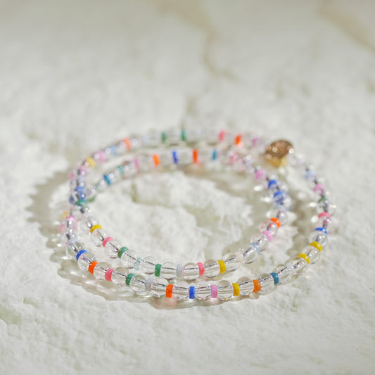 A double-row stretch bracelet made with clear crystal quartz and rainbow color beads. Light, joyful, and handmade by Gina Kim Jewelry