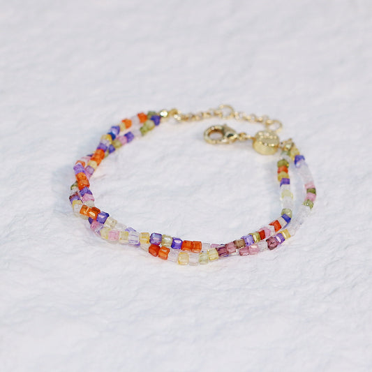 GinaKim Joy Prism Bracelet on wrist, featuring a vibrant mix of colorful cubic beads with a white shell button clasp, adding a touch of elegance and sparkle. Perfect for daily wear and casual chic style.