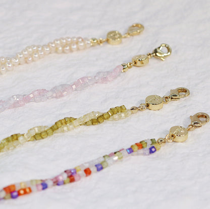 Angled close-up of four bracelets—Joy, Olive, Blush Prism, and Double Grace Pearl—showcasing cubic zirconia sparkle and soft pastel hues, styled for a refined and elegant look.