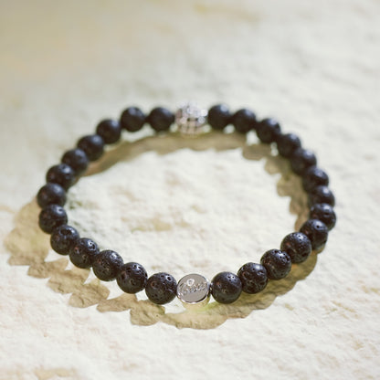 A natural lava stone stretch bracelet with silver accents and a Gina Kim logo charm. Bold, grounding, and handmade