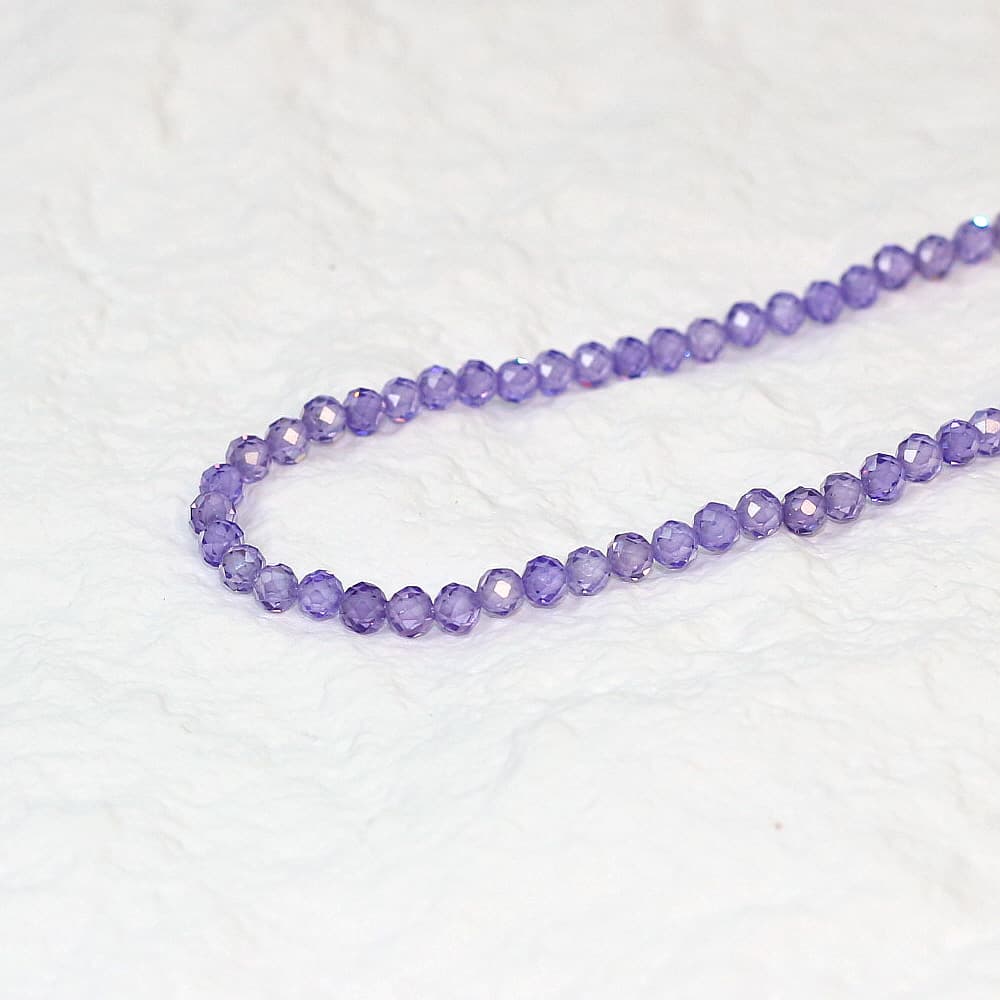 Detailed close-up of faceted lavender CZ beads from the Lavender Light Necklace, emphasizing clarity and cut.