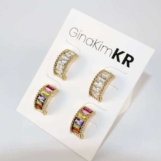 Product card featuring Lumière Arc Earring Set under warm lighting, with both crystal-accented gold pairs displayed front-facing.