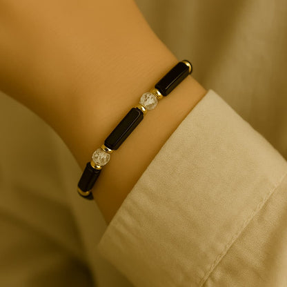 Close-up of a woman's wrist wearing the Midnight Focus Bracelet by Gina Kim, featuring sleek rectangular black gemstone beads, faceted clear crystal CZ stones, and gold-tone accents for a bold and elegant look