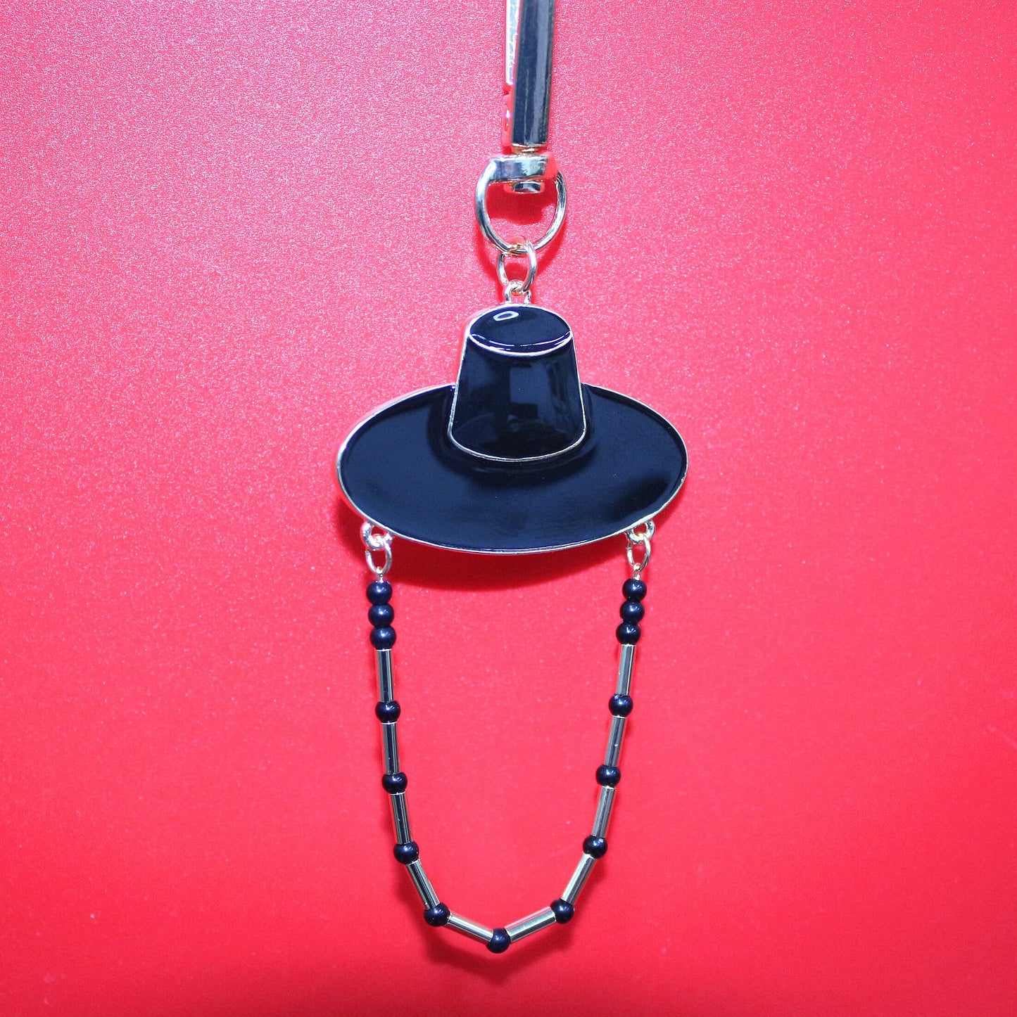 Black Korean hat motif key ring against a red background showing K POP shadow style inspired by JINU.
