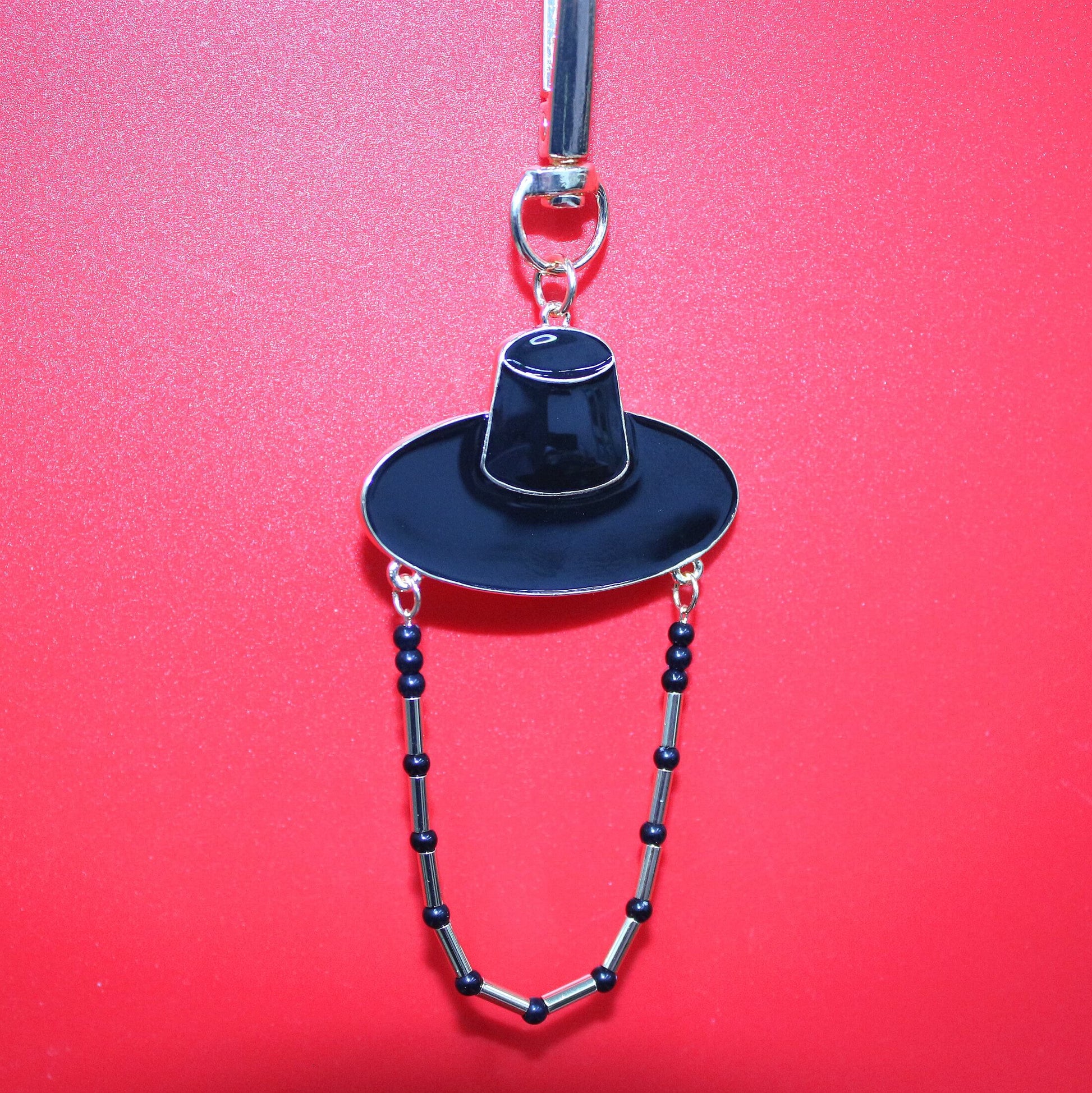 Black Korean hat motif key ring against a red background showing K POP shadow style inspired by JINU.