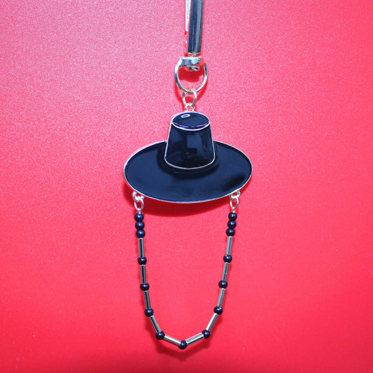 Black Korean hat motif key ring against a red background showing K POP shadow style inspired by JINU.