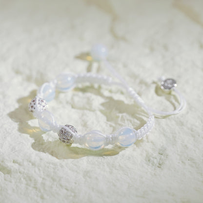 A handmade moonstone bracelet with silver-toned accents, featuring a soft glow and adjustable macramé closure with Gina Kim charm.