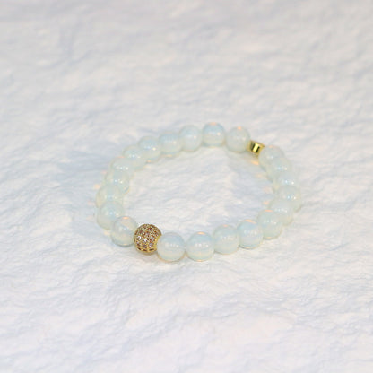 Front-facing flat-lay of the Moonstone Strength Bracelet with milky-white beads and warm gold-tone details, displayed on a soft neutral background.