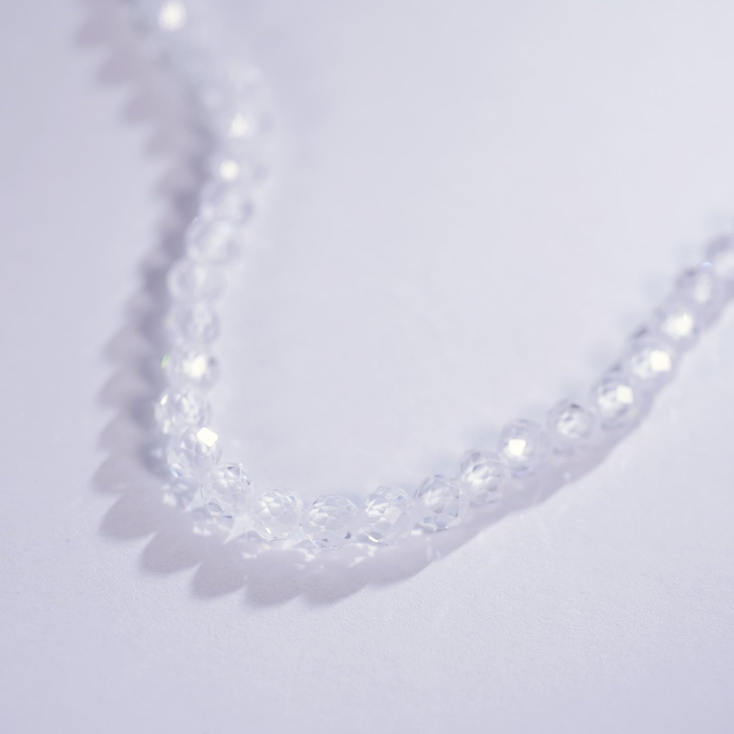 Close-up of the Morning Light Necklace laid on a light purple surface, showing faceted CZ clarity and minimalist Korean design by GinaKimKR.