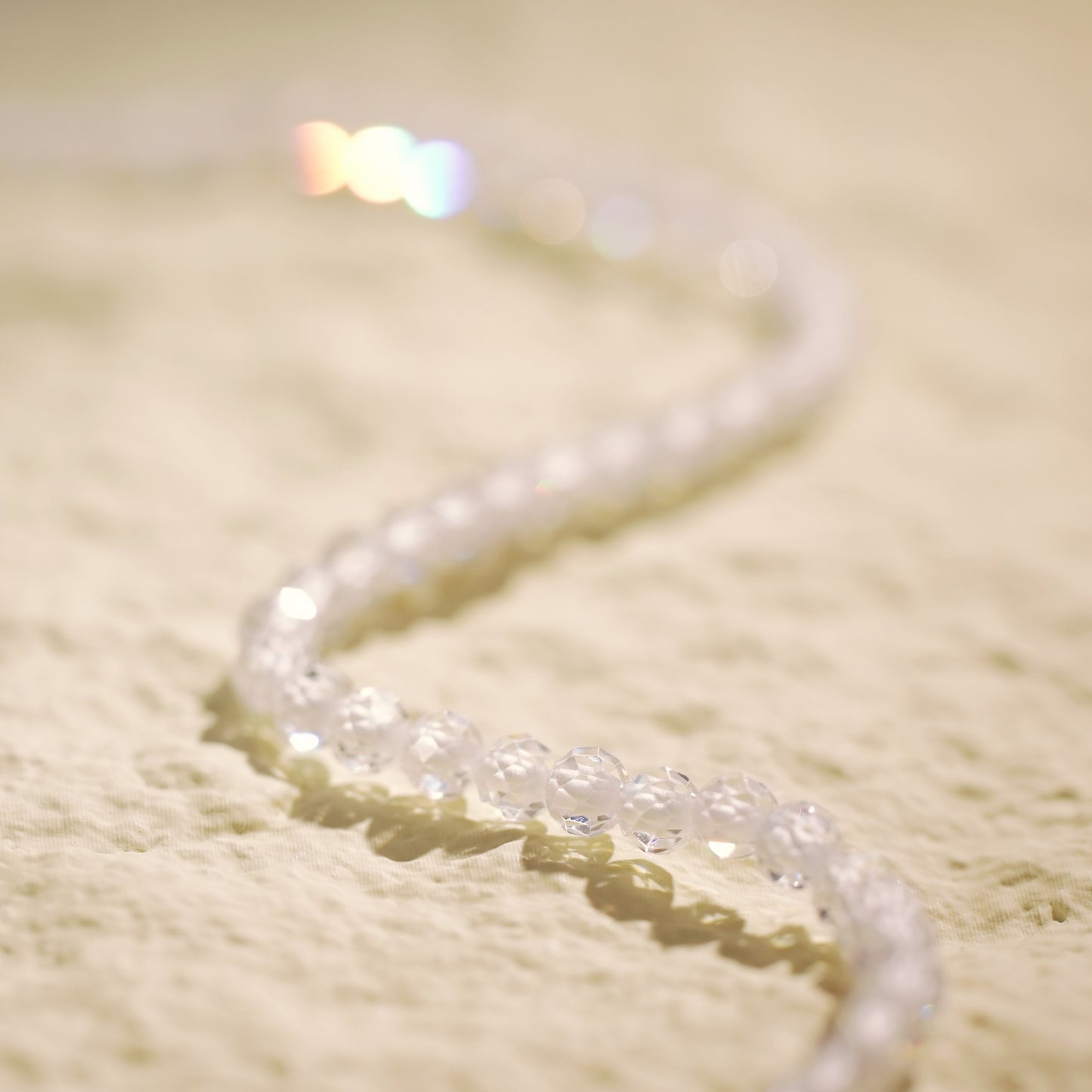 Top-down view of the Morning Light Necklace arranged in an S-curve, showing the shimmer of clear CZ beads and delicate gold-plated finishing touches.
