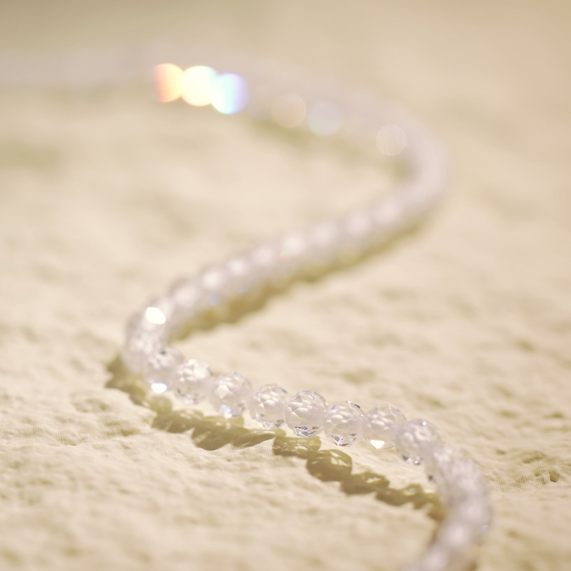Top-down view of the Morning Light Necklace arranged in an S-curve, showing the shimmer of clear CZ beads and delicate gold-plated finishing touches.