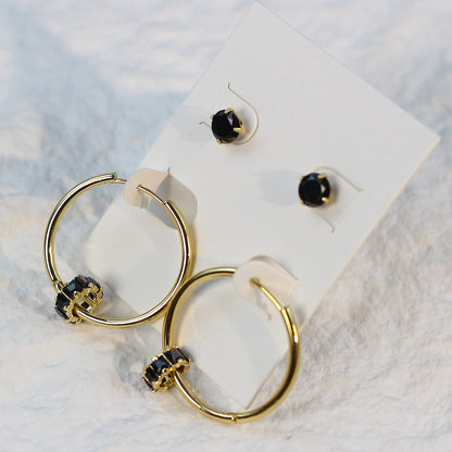Soft daylight view of Noir Balance Earring Set on a cream card, emphasizing the contrast between jet crystals and polished gold hoops.