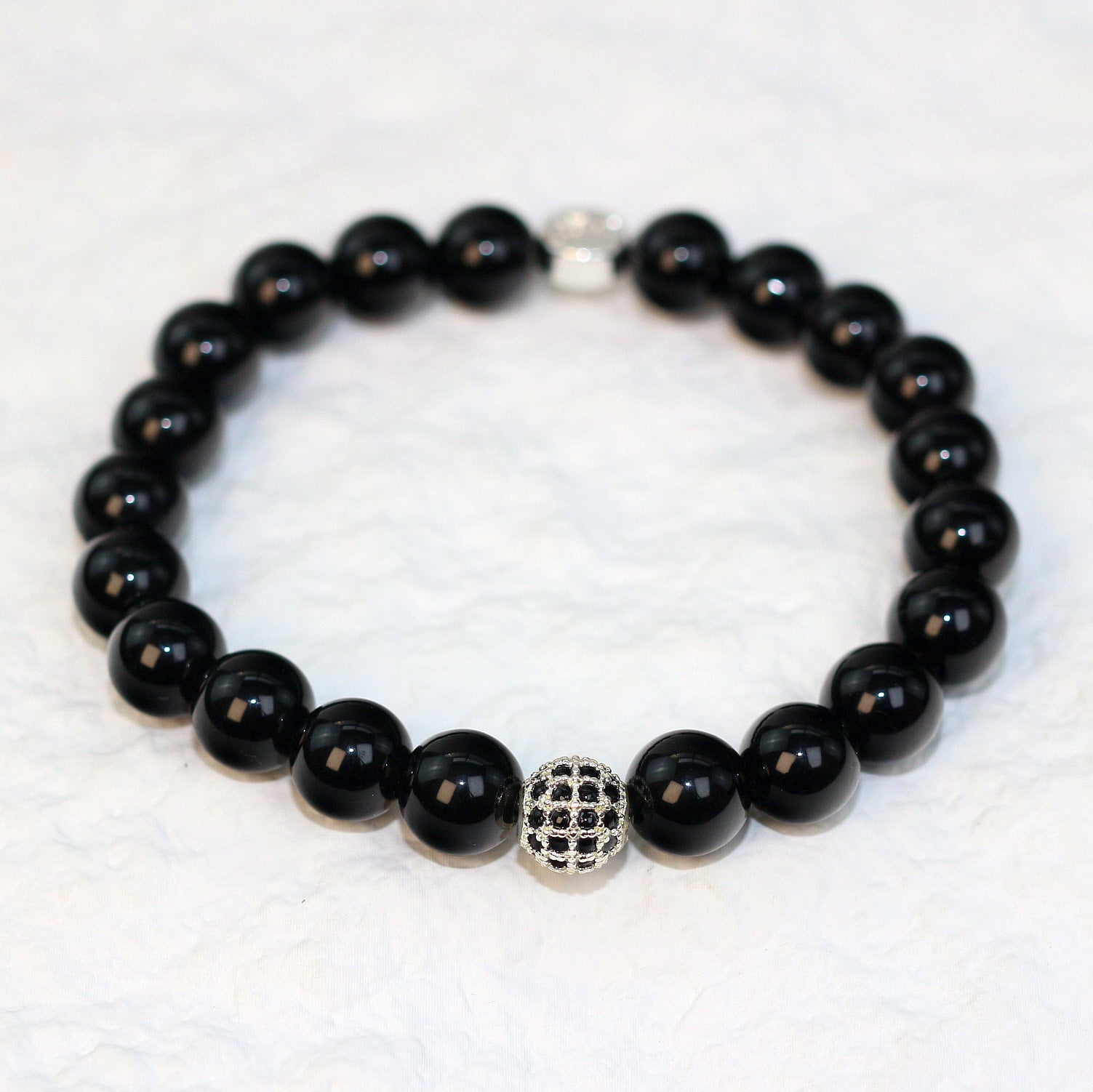 Front-facing shot of the Onyx Strength Bracelet showcasing the deep black hue and shine of 8mm round natural onyx beads.