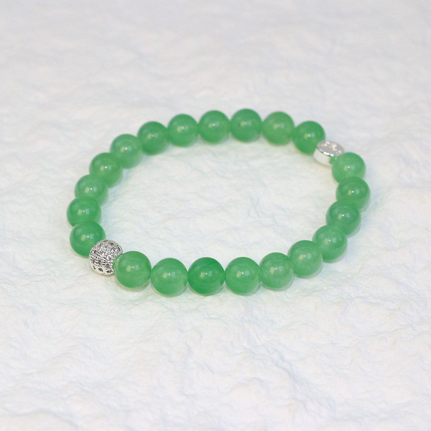 Top-down view of the Peridot Strength Bracelet featuring 8mm round beads in a refreshing green hue, neatly arranged on a white surface.