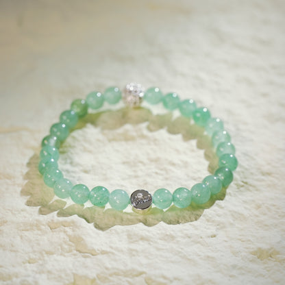 A stretch bracelet made with light green peridot beads, a gold CZ accent, and a Gina Kim logo charm. Bright, fresh, and handmade.