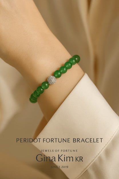 Close up - A woman wearing the Peridot Fortune Bracelet by Gina Kim, featuring green peridot stones with a gold CZ bead. Light, joyful, and elegant.