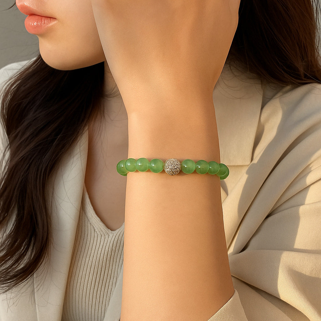 A woman wearing the Peridot Fortune Bracelet by Gina Kim, featuring green peridot stones with a gold CZ bead. Light, joyful, and elegant.